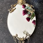 Antique French Neo-Renaissance small oval brass wall mirror detailed with a sculpted profile cameo of a noble woman and ornate openwork scroll details.