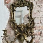 Heavy mirrored wall sconce in neo-rococo style with mascaron and lattice details