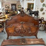 Exquisite louis xv style bed in carved walnut featuring deep relief cherub motifs and elegant parcel-gilt accents.