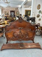 Exquisite louis xv style bed in carved walnut featuring deep relief cherub motifs and elegant parcel-gilt accents.