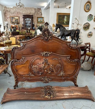 Exquisite louis xv style bed in carved walnut featuring deep relief cherub motifs and elegant parcel-gilt accents.