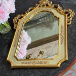 Elegant gilt neo-rococo wall mirror featuring a wooden frame with floral scrolls and a pastel green craquelure finish.