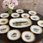 Beautiful limited edition limoges porcelain fish service including a large platter and ten plates with hand-painted fish motifs and heavy gold rims in Naturalism style.
