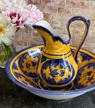 Bright yellow and blue hand-painted ceramic majolica pitcher and basin set with floral motifs in Majolica style.