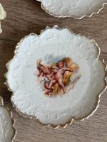 Trīs porcelāna deserta šķīvīši ar putti eņģeļu ainām, reljefu arabesku apmali un zelta malu — Neobaroks / Historicisms, Vācija vai Bohēmija, ap 1880.–1900. gads, 3 gab. (5557) - Image 2
