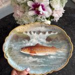 "Limoge" porcelāna šķīvis, apgleznots ar zivs motīvu un zelta krāsas detalizāciju, neliela izmēra (6950)