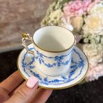Antique French porcelain tea cup and saucer with hand-painted blue ribbons and floral wreaths