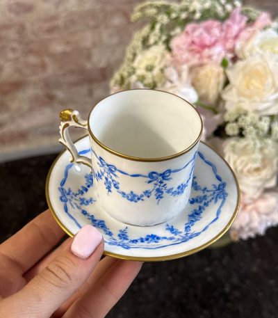 Antique French porcelain tea cup and saucer with hand-painted blue ribbons and floral wreaths