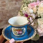 Antique porcelain tea cup and saucer with blue glaze and hand-painted flowers
