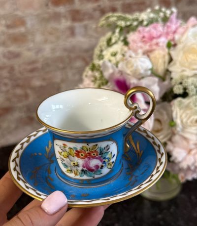 Antique porcelain tea cup and saucer with blue glaze and hand-painted flowers