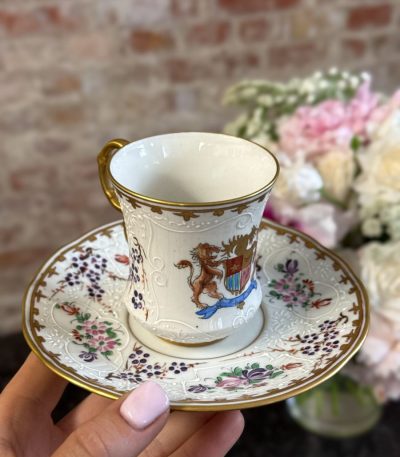 antique armorial porcelain cup and saucer with coat of arms and raised white enamel