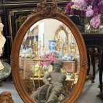 Antique French Rococo style walnut oval wall mirror with detailed shell cartouche cresting and thick bevelled glass.
