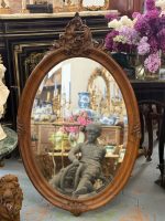 Antique French Rococo style walnut oval wall mirror with detailed shell cartouche cresting and thick bevelled glass.