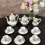 Antique white porcelain tea service with delicate violet floral motifs and gold trim