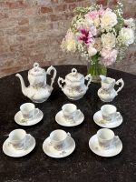 Antique white porcelain tea service with delicate violet floral motifs and gold trim