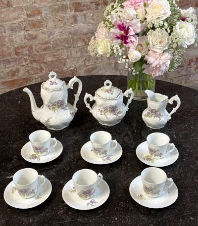 Antique white porcelain tea service with delicate violet floral motifs and gold trim