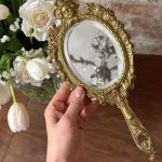 gilt bronze hand mirror with cherub
