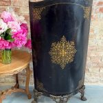 Antique black tole firescreen with gilt ornament and lion-paw feet