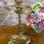 Antique French Victorian style gold patinated cast iron umbrella stand featuring a detailed rococo scrollwork frame and a removable drip tray base.