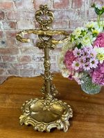 Antique French Victorian style gold patinated cast iron umbrella stand featuring a detailed rococo scrollwork frame and a removable drip tray base.