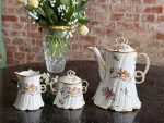 Antique French porcelain tea set with floral motifs and gold trim`