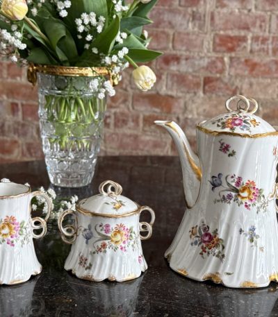 Antique French porcelain tea set with floral motifs and gold trim`